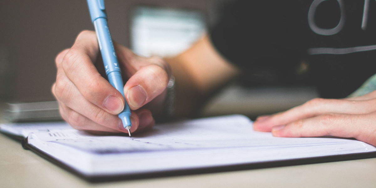 person writing in journal on table